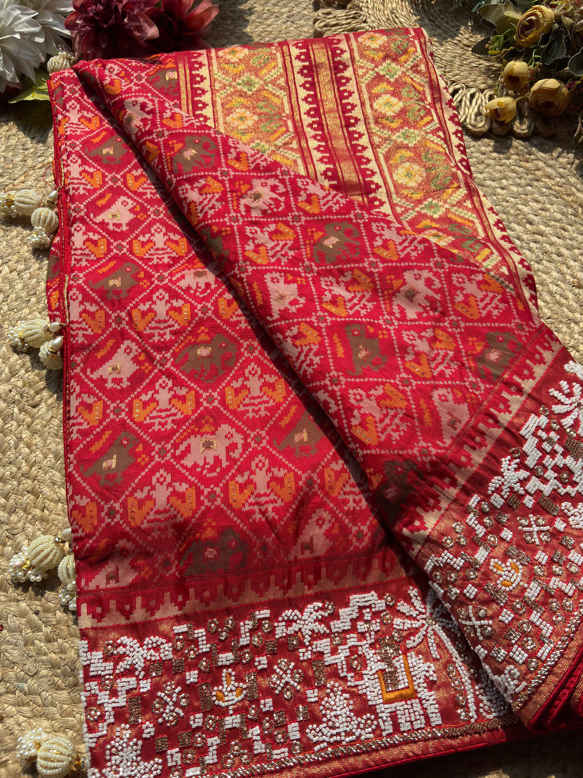 Royal Red Patola-Inspired Designer Saree with Golden Zari-Style Border, Multicolour Floral Motifs, Intricate White Beadwork and Pearl Tassel Detailing