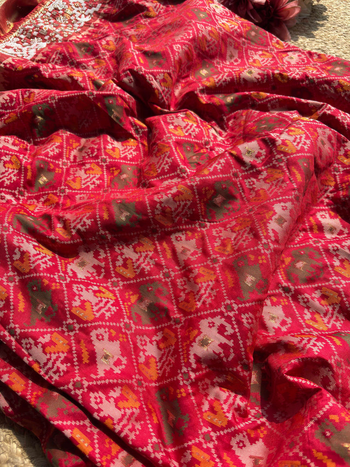 Royal Red Patola-Inspired Designer Saree with Golden Zari-Style Border, Multicolour Floral Motifs, Intricate White Beadwork and Pearl Tassel Detailing